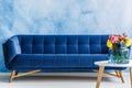 Comfortable navy blue plush sofa and colorful flowers in a vase