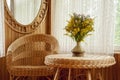 A comfortable place with wicker furniture. Mirror, armchair, table and window. Summer mood.