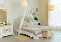 Comfortable simple bedroom with light-colored furniture, four-poster bed, feather lamps, small fireplace on wood, cosy modern Royalty Free Stock Photo