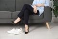Comfortable sneakers near businesswoman wearing high heel shoes indoors, closeup Royalty Free Stock Photo