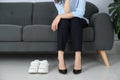 Comfortable sneakers near businesswoman wearing high heel shoes indoors, closeup Royalty Free Stock Photo