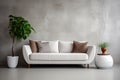 Comfortable stylish sofa with brown and white designer pillows against a gray wall and two green plants in the corners. Minimalist Royalty Free Stock Photo