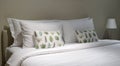 Comfortable throw cushion on the white pillow s and white bedsheet with three hanging picture frames