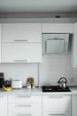 Comfortable white kitchen with a white lacquered facades. Modern kitchen clean interior design. Cookstove, toaster and