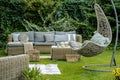 Wicker garden furniture with grey pillows in beautiful backyard