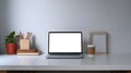 Comfortable workplace with laptop, coffee cup, house plant, book and pencil holder on white table. Royalty Free Stock Photo