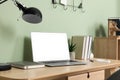 Comfortable workplace at home. Modern laptop with blank screen and lamp on wooden desk. Mockup for design Royalty Free Stock Photo