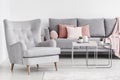 Comfy armchair and grey sofa with pink pillows, and coffee table Royalty Free Stock Photo