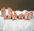 Comfy family lying in a bed together relaxing taking a nap together. Feet and toes of parents and their children being Royalty Free Stock Photo