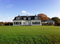 A comfy white mansion surrounded by a perfect lawn