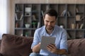 Focused millennial guy student enjoy using digital tablet at home