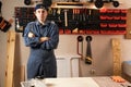 Comic young carpenter making fish lips and looking at the camera to assemble furniture working in studio or workshop with tools on Royalty Free Stock Photo