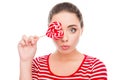 Comic young woman holding a lollipop near her eyes and pouting