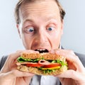 Comical man eating sandwich with funny expression Royalty Free Stock Photo