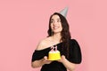 Coming of age party - 21st birthday. Smiling woman holding delicious cake with number shaped candles on pink background Royalty Free Stock Photo