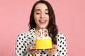 Coming of age party - 18th birthday. Smiling woman holding delicious cake with number shaped candles on pink background Royalty Free Stock Photo