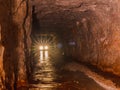 Car lights from inside deep old mining tunnel cave with reflection. rock wall cave with water lodge rocky road. adventure travel Royalty Free Stock Photo