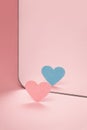 Coming out. Pink paper heart in front of a mirror. Blue heart reflected.