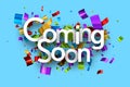 Coming soon with colorful cut out foil ribbon confetti on blue background Royalty Free Stock Photo