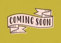 Coming Soon lettering or inscription written with modern font on elegant ribbon or tape isolated on yellow background