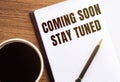 COMING SOON STAY TUNED. Text on notepad on wooden desk Royalty Free Stock Photo