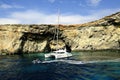 Catamaran at anchor below the cliffs of Comino