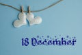 Commemorative date of 18 December on a blue background with white hearts with clothespins, flat lay. Holiday calendar concept.