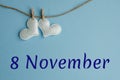 Commemorative date November 8 on a blue background with white hearts with clothespins, flat lay. Holiday calendar concept