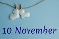 Commemorative date November 10 on a blue background with white hearts with clothespins, flat lay. Holiday calendar concept World