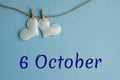 Commemorative date October 6 on a blue background with white hearts with clothespins, flat lay. Holiday calendar concept