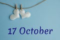 Commemorative date October 17 on a blue background with white hearts with clothespins, flat lay. Holiday calendar