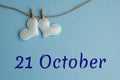 Commemorative date October 21 on a blue background with white hearts with clothespins, flat lay. Holiday calendar