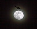 Commercial Airliner Passing a Full Moon at Night