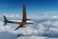 Commercial airplane flying above clouds and clear blue sky over Royalty Free Stock Photo