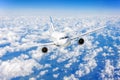 Commercial airplane flying over bright blue sky and white clouds. Royalty Free Stock Photo