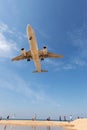 Commercial airplane landing above sea and clear blue sky over be Royalty Free Stock Photo