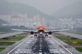 Commercial airplane landing at sunset hours in Asia, telephoto lens.