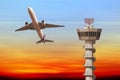 Commercial airplane take off over airport control tower at sunse