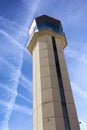 Commercial Airport Control Tower from close up perspective with sky criss-crossed by jet trails