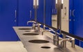 Commercial bathroom for hand washing. Faucets with a washbasin in a public toilet are blue. Royalty Free Stock Photo