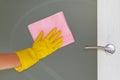 Commercial cleaning company concept. Hand in rubber protective glove with pink microfiber cloth is wiping glass door Royalty Free Stock Photo