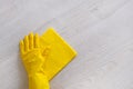 Commercial cleaning company concept. Hand in rubber protective glove with yellow microfiber cloth is wiping wooden floor. Copy Royalty Free Stock Photo