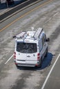 Commercial compact cargo mini van with ladders on the roof driving on the turning overpass road intersection