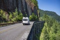 Commercial freight compact cargo mini van running on the overpass mountain road with rock wall on the one side and abyss on the