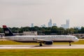 Commercial jet on an airport runway with city skyline in the background.