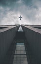 Low angle view of modern tall business building. Commercial jet plane flying over skyscraper. Against dramatic cloudy Royalty Free Stock Photo