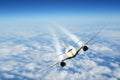 Commercial passenger airplane flying above the clouds with condensation contrails