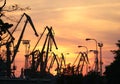 Commercial port cranes silhouettes at sunset, red sky background