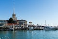 Commercial seaport of Sochi. City center with spike of main building tower Marine Station. Ships, yachts and boats on blue surface