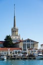 Commercial seaport of Sochi. City center with spike of main building tower Marine Station. Ships, yachts and boats on blue surface